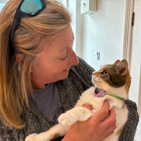 Paula holding a tabby and white cat, the two of them looking at each other